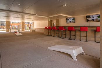 a white coffee table sits in the middle of a large room with stools on the wall  at Avant & Avant II, Carmel, 46032